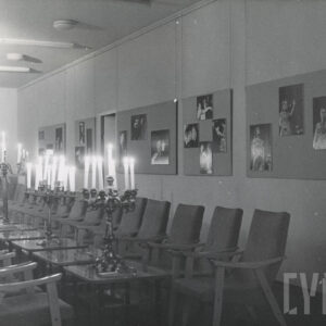 sala wystawowa, na ścianach zaprezentowane zdjęcia w dużych formatach, głównie portrety muzyków grających na skrzypcach, pośrodku kilkanaście kwadratowych, niskich stolików, stojących jeden za drugim, przy nich fotele, na stolikach świeczniki