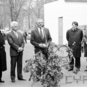 grupa mężczyzn w garniturach na tle jednego z pawilonów targowych