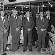 grupa ludzi ubrana w eleganckie stroje stojąca w jednym z pawilonów targowych