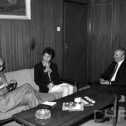 jedna kobieta i dwóch mężczyzn w średnim wieku, siedzący przy stole zastawionym w słodycze