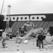 grupa mężczyzn przyglądająca się maszynom budowlanym wystawionym na placu