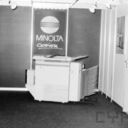 kserokopiarka stojąca na tle ścianki z napisami