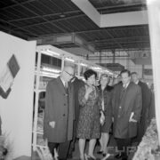 dwie kobiety i kilku mężczyzn w płaszczach w hali wystawowej