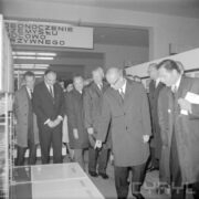 grupa mężczyzn, część w płaszczach w hali wystawowej