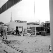 murowany budynek, trzech mężczyzn stoi, przed budynkiem gruz i fragmenty kartonów