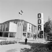murowany budynek, przed nim zwiedzający ludzie, z prawej w pionie litery DDR