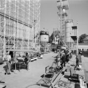 stoisko z rusztowaniami, przed rusztowaniami podnośniki samochodowe, urządzenia, wystawie przyglądają się mężczyźni, w głębi silosy