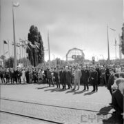 duża grupa ludzi, za nimi ażurowy model kuli ziemskiej i maszty z flagami państw