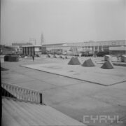 plac otoczony halami, na środku rozstawione namioty turystyczne