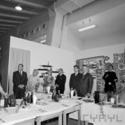 grupa kobiet i mężczyzn stojących przy zastawionym stole w hali wystawowej