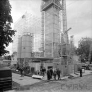 stoisko z rusztowaniami, silosami na terenie placu, wystawie przyglądają się mężczyźni