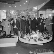 grupa ludzi ogląda stoisko z butami w pawilonie wystawowym