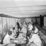 kobiety i mężczyźni siedzą przy zastawionych stolikach