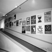 plakaty wiszące w dwóch rzędach na ścianie