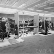 stoiska z ubranymi manekinami i torebkami w hali wystawowej, w głębi na ścianie zdjęcie gór