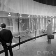 stoisko z modelami śmigłowców w pawilonie wystawowym, przy stoisku stoi dwóch mężczyzn