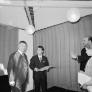 trzech mężczyzn, jeden z nich trzyma w rękach dyplom, z prawej częściowo widoczna dziewczynka w stroju harcerki