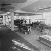 maszyny w hali wystawowej, przy nich oglądający ludzie