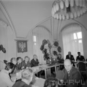 grupa mężczyzn i kobiet siedząca przy stole, ustawionym w kształcie litery U