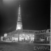 stoiska plenerowe nocą, w głębi iglica pawilonu wystawowego