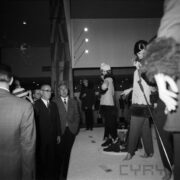 grupa mężczyzn ogląda stoisko z odzieżą damską w hali targowej