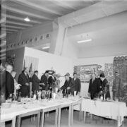 duża grupa kobiet i mężczyzn stojących przy zastawionym stole w hali wystawowej