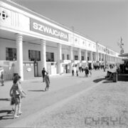 budynek murowany z podcieniami i kolumnadą wzdłuż budynku, zwiedzający ludzie