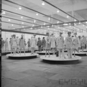 stoiska z ubranymi manekinami w hali wystawowej