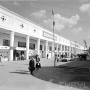 budynek otynkowany z podcieniami i kolumnadą wzdłuż budynku, zwiedzający ludzie