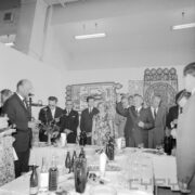 grupa kobiet i mężczyzn stojących przy zastawionym stole w hali wystawowej