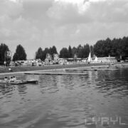 tory regatowe nad jeziorem, w głębi namioty pawilony i spacerujący i opalający się ludzie