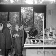 grupa rozmawiających ze sobą mężczyzn, stojących przy stoisku z butami w hali wystawowej