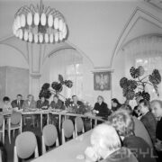 grupa mężczyzn siedzi przy stole, ustawionym w kształcie litery U