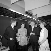 dwie kobiety i dwóch mężczyzn w pawilonie wystawowym, para w środku trzyma w rękach szklanki