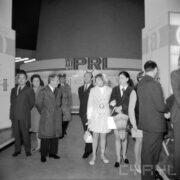 grupa kobiet i mężczyzna, część z nich w płaszczach, w hali wystawowej