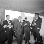 grupa mężczyzn na tarasie budynku, część z nich trzyma w rękach kieliszki