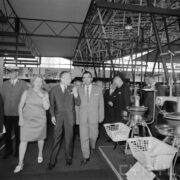 jedna kobieta i grupa mężczyzn w hali wystawowej