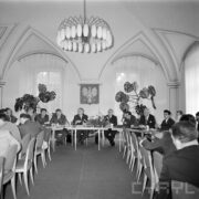 grupa mężczyzn i kobiet siedząca przy stole, ustawionym w kształcie litery U