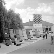 wystawa dmuchanych materacy, za nimi drzewa, w głębi budynek ze skośnym dachem, z prawej spacerują ludzie