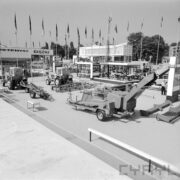 stoisko z maszynami rolniczymi, w głębi murowany budynek