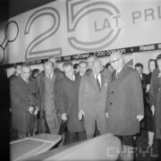 grupa mężczyzn w płaszczach w hali wystawowej