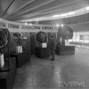 stoisko w formie czterech prostopadłościanów, na których postawiono silniki lotnicze, przed nimi stoi odwrócony tyłem mężczyzna