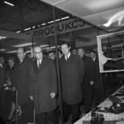 grupa ludzi w płaszczach w hali wystawowej