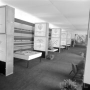 stoisko w hali wystawowej, z prawej fragment osoby siedzącej na fotelu