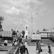 spacerujący ludzie po terenach targowych, w głębi wystawa dźwigów budowlanych