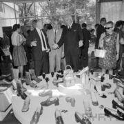 grupa ludzi ogląda stoisko z butami w pawilonie wystawowym