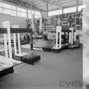 stoiska z urządzeniami w hali wystawowej, pomiędzy nimi zwiedzający ludzie