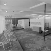 stoiska z drewnianymi leżakami, krzesłami i komodami w pawilonie wystawowym