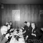 grupa mężczyzn siedzących przy niskim, zastawionym stole