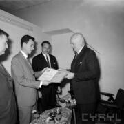 czterech mężczyzn, dwóch z nich trzyma wspólnie w rękach dyplom